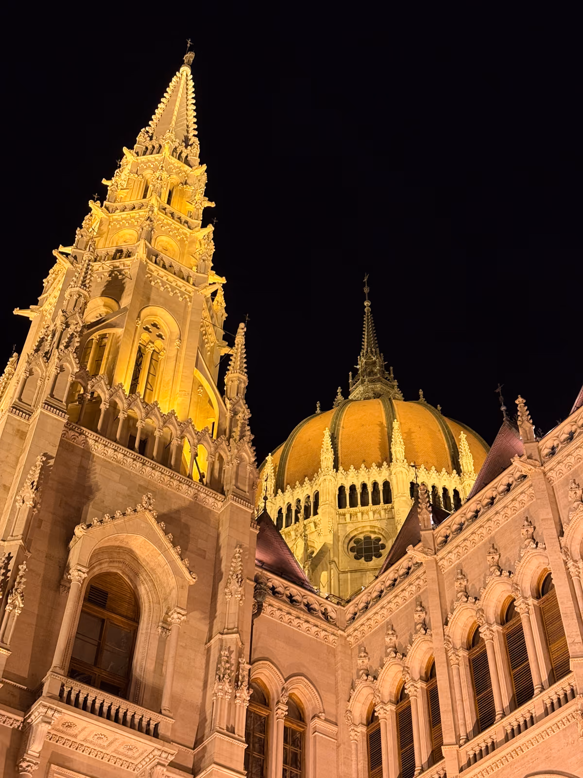 The Hungarian Parliament's spire and dome lit gold against the night sky