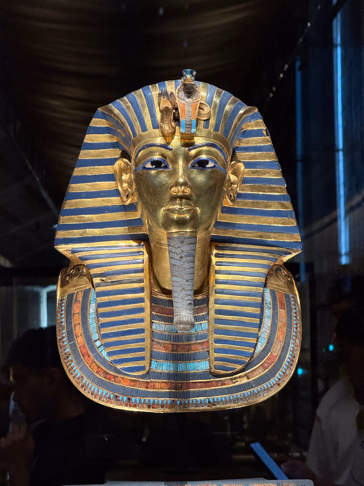 The gold death mask of Tutankhamun in a dark museum hall